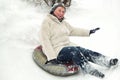 Cheerful smiling elderly mature woman riding on snow tubing. Senior lady sledding slide down hill. Winter fun activity outdoor. Royalty Free Stock Photo