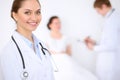 Cheerful smiling female doctor on the background with doctor and his patient in the bed. High level and quality of Royalty Free Stock Photo