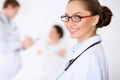 Cheerful smiling female doctor on the background with doctor and his patient in the bed. High level and quality of Royalty Free Stock Photo