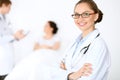 Cheerful smiling female doctor on the background with physician and his patient in the bed Royalty Free Stock Photo