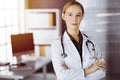 Cheerful smiling female doctor standing with arms crossed in clinic. Portrait of friendly physician woman. Medicine Royalty Free Stock Photo