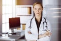 Cheerful smiling female doctor standing in clinic. Portrait of friendly physician woman. Medical service in hospital