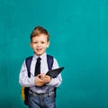 Cheerful smiling little boy with big backpack holding digital ta Royalty Free Stock Photo