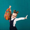 Cheerful smiling little girl with big backpack jumping and having fun against blue wall. Royalty Free Stock Photo