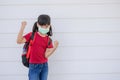 Cheerful smiling little girl with big backpack jumping and having fun against the white wall. Looking at the camera. School Royalty Free Stock Photo