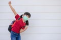 Cheerful smiling little girl with big backpack jumping and having fun against the white wall. Looking at the camera. School Royalty Free Stock Photo