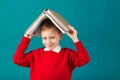 Cheerful smiling little school boy with big books on his head ha Royalty Free Stock Photo