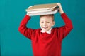 Cheerful smiling little school boy with big books on his head ha Royalty Free Stock Photo