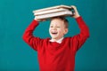 Cheerful smiling little school boy with big books on his head ha Royalty Free Stock Photo