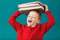 Cheerful smiling little school boy with big books on his head ha Royalty Free Stock Photo