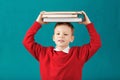 Cheerful smiling little school boy with big books on his head ha Royalty Free Stock Photo