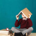 Cheerful smiling little school boy with big books on his head ha Royalty Free Stock Photo