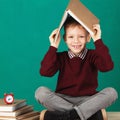 Cheerful smiling little school boy with big heavy books on his h Royalty Free Stock Photo