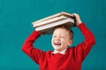 Cheerful smiling little school boy with big books on his head ha Royalty Free Stock Photo