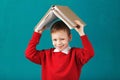 Cheerful smiling little school boy with big books on his head ha Royalty Free Stock Photo