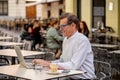 Cheerful smiling old man working on computer while having coffee in terrace coffee shop city outdoors in seniors using modern Royalty Free Stock Photo