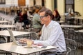 Cheerful smiling old man working on computer while having coffee in terrace coffee shop city outdoors in seniors using modern Royalty Free Stock Photo