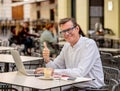 Cheerful smiling old man working on computer while having coffee in terrace coffee shop city outdoors in seniors using modern Royalty Free Stock Photo