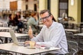 Happy attractive stylish mature man working on laptop showing thumb up in outside coffee shop Royalty Free Stock Photo