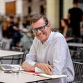 Cheerful smiling old man working on computer while having coffee in terrace coffee shop city outdoors in seniors using modern Royalty Free Stock Photo