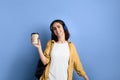 Cheerful smiling student girl is walking keeping takeaway coffee cup in hand, enjoys morning before school, well prepared for test Royalty Free Stock Photo