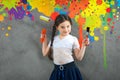 Cheerful smiling young little girl the child draws on the background wall colored paints making a creative repairs.