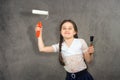 Cheerful smiling young little girl the child draws on the background wall colors making a creative repairs.