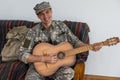 Cheerful smiling young military man wearing khaki uniform holding guitar. Royalty Free Stock Photo