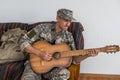 Cheerful smiling young military man wearing khaki uniform holding guitar. Royalty Free Stock Photo