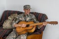 Cheerful smiling young military man wearing khaki uniform holding guitar. Royalty Free Stock Photo
