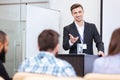 Cheerful speaker standing at the tribune in conference hall