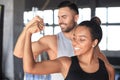 Cheerful sportive couple training together and showing biceps at the gym Royalty Free Stock Photo