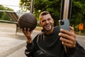 Cheerful sportsman taking selfie with basketball ball on sports court Royalty Free Stock Photo