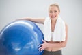 Cheerful sporty blonde with towel around her neck holding exercise ball Royalty Free Stock Photo
