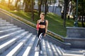 Cheerful sporty girl drinking water, standing on stairs at park Royalty Free Stock Photo