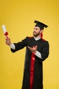 Cheerful student holding, raising diploma, looking up.