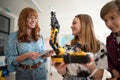 Cheerful students showing their builded robotic toy to young science teacher at robotics classroom at school.