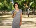 Smiling female with a green smoothie. Healthy women on a blurred park background. Healthy lifestyle concept. Copy space. Royalty Free Stock Photo