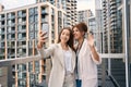 Cheerful stylish business ladies taking selfie outside