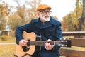 cheerful stylish senior man playing on acoustic guitar