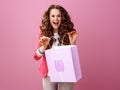 Cheerful stylish woman isolated on pink with shopping bag