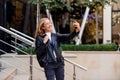 Cheerful beautiful student girl has online video conversation on smart phone on the street, enjoying walk outdoors. Royalty Free Stock Photo