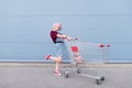 Cheerful stylish young girl in jeans jacket, shoes and skirt, listening to music in headphones with phone Royalty Free Stock Photo