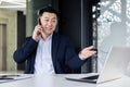 Cheerful and successful asian businessman working inside office at workplace, boss talking smiling on phone, man in Royalty Free Stock Photo