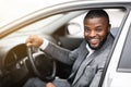 Cheerful successful black businessman looking through car window