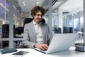 Cheerful and successful businessman inside office working with laptop, bearded man smiling and typing on laptop keyboard Royalty Free Stock Photo