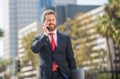 cheerful successful businessman in suit talking on phone standing outdoor, mobile technology Royalty Free Stock Photo