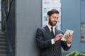 Cheerful and successful businessman works outdoors near the office holds a tablet, smiles reads good news Royalty Free Stock Photo