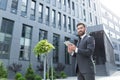 Cheerful and successful businessman works outdoors near the office holds a tablet, smiles reads good news Royalty Free Stock Photo