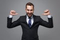 Cheerful successful young business man in classic black suit shirt tie posing isolated on grey background. Achievement Royalty Free Stock Photo